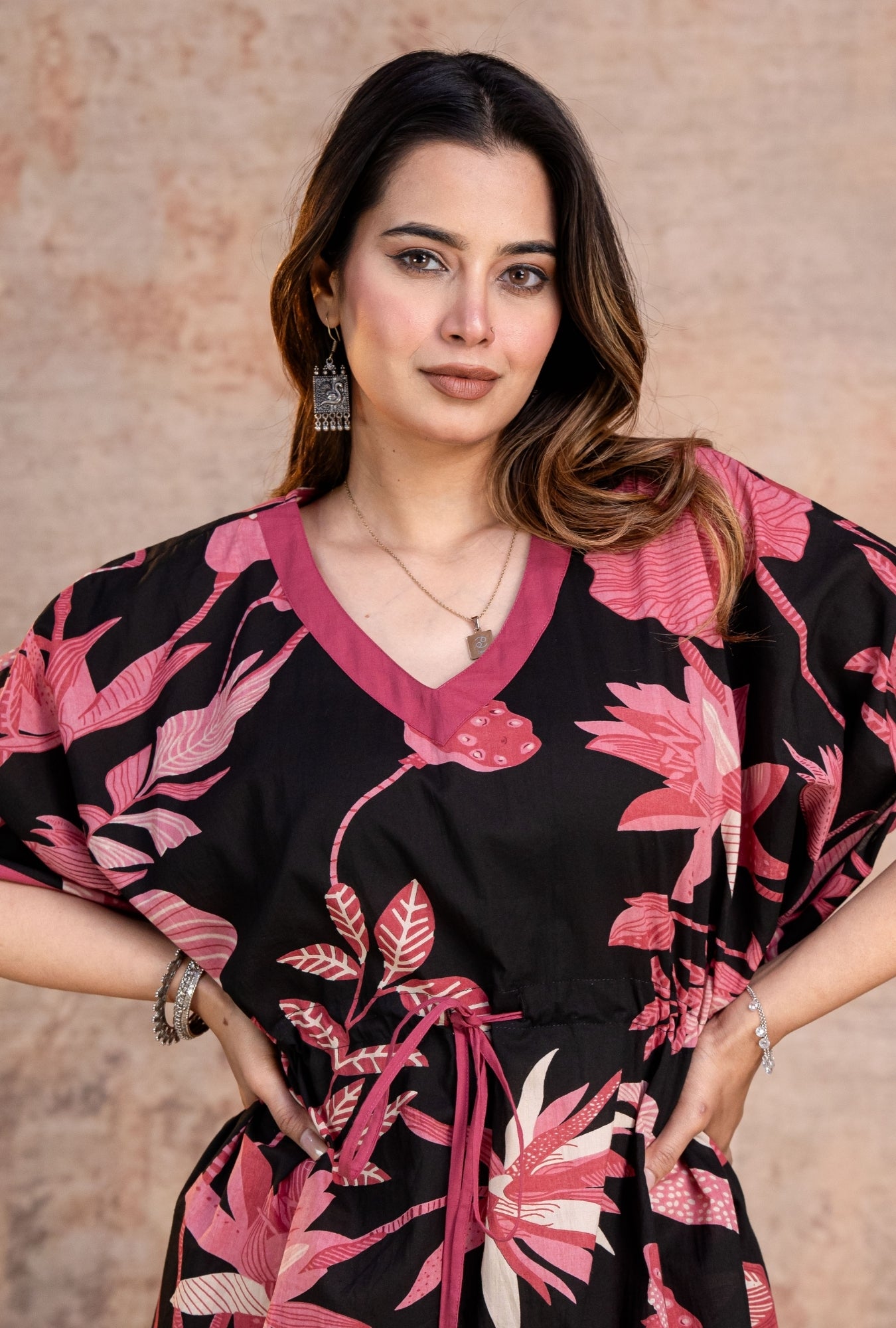Woman wearing a black kaftan with pink floral patterns 