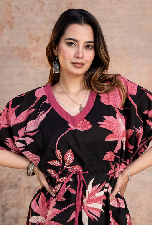 Woman wearing a black kaftan with pink floral patterns 